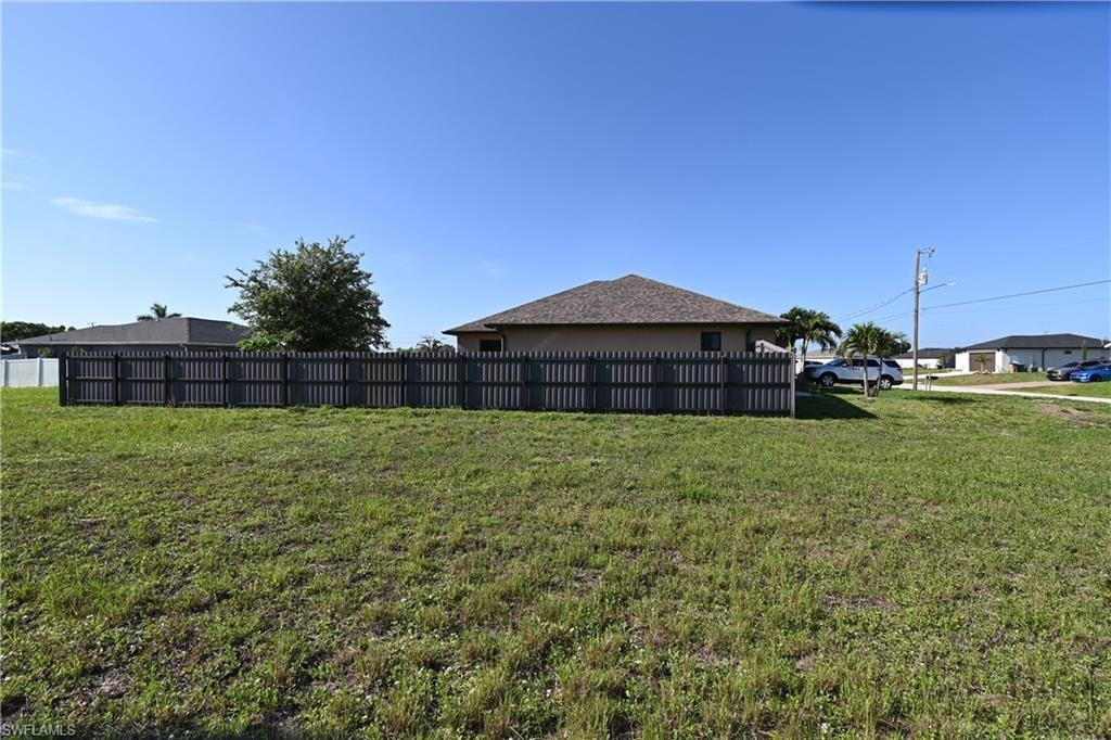 Expansive lot featuring a dark-toned privacy fence and a one-story dwelling with a hip roof