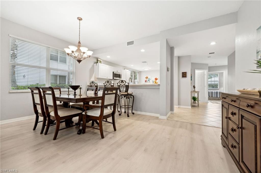 Dining area with a notable chandelier, a wealth of natural light, and light wood-type flooring