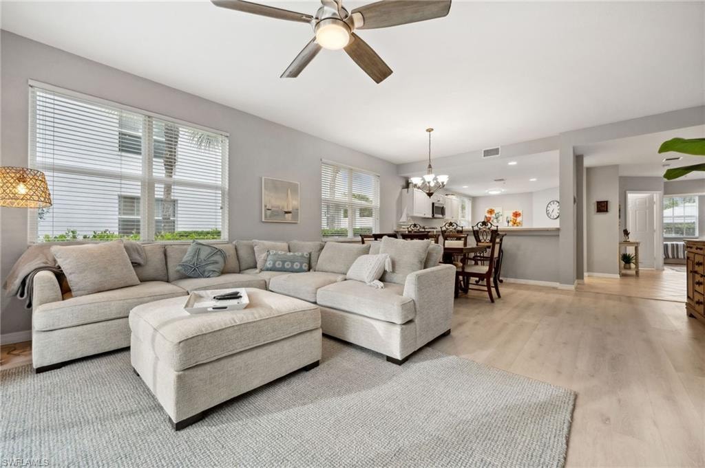Living room with light hardwood / wood-style flooring and ceiling fan with notable chandelier