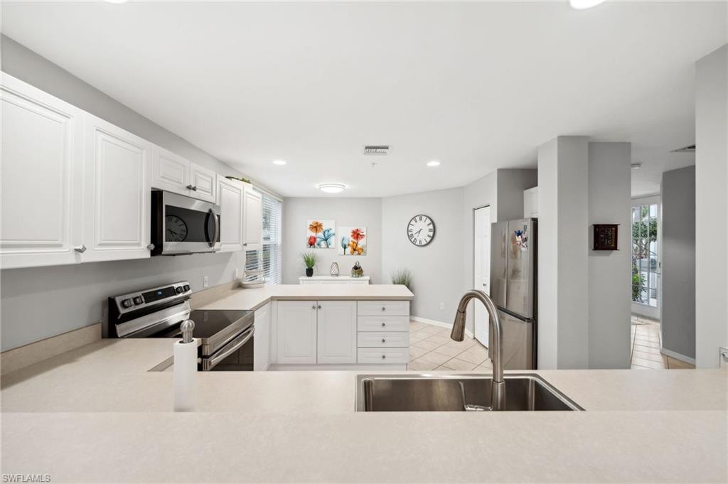 Kitchen featuring appliances with stainless steel finishes, white cabinetry, sink, and light tile patterned flooring