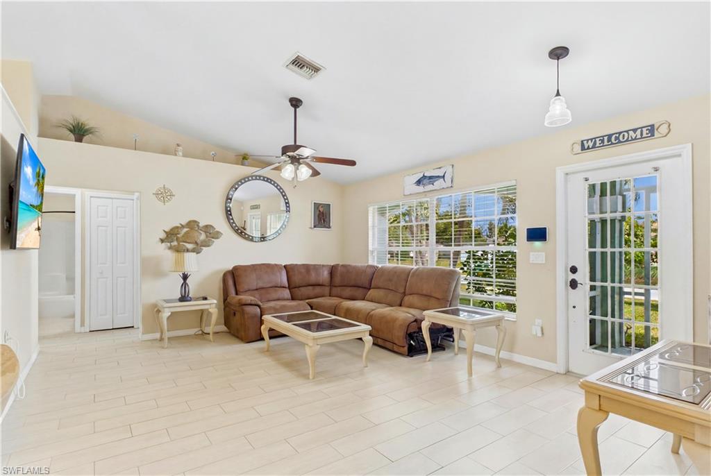 Spacious living area featuring tile flooring, vaulted ceilings, and a ceiling fan with integrated lighting