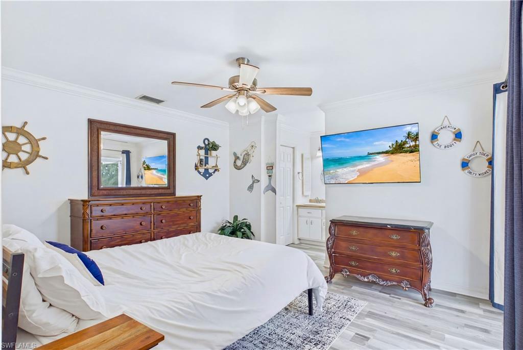 Spacious room featuring wood-finish flooring, crown molding, and a ceiling fan