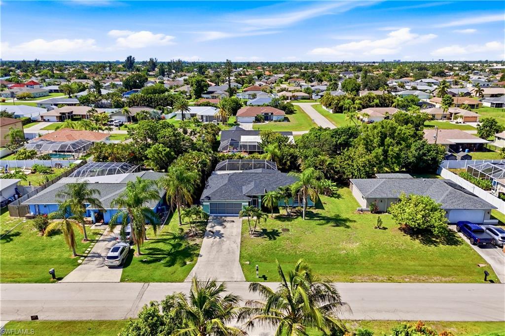 Residential property featuring a screened pool enclosure, mature palm trees, a concrete driveway, and a shingle roof