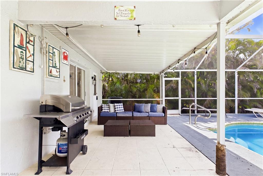 Screened lanai featuring a covered patio, tiled flooring, and an in-ground swimming pool with handrails