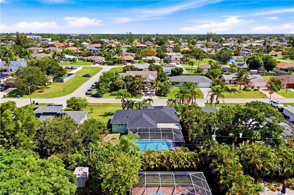 Residential property with a screened swimming pool, surrounded by mature trees and landscaping