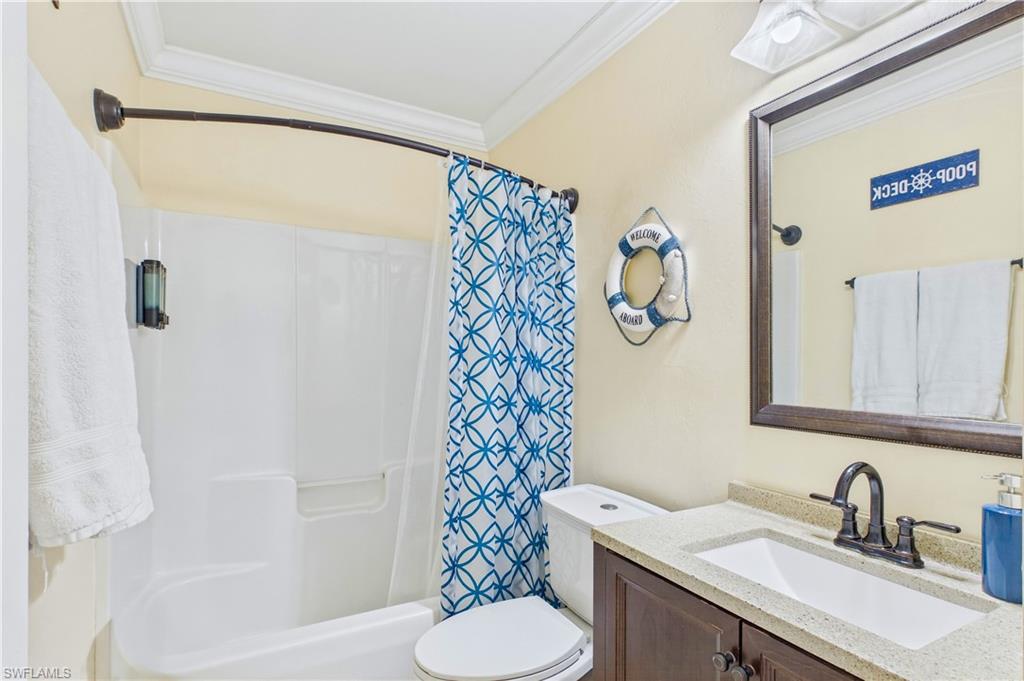 Bathroom featuring a white tub/shower combination with a curved shower rod, a dark wood-finish vanity with a light-colored countertop, and an integrated sink with a dark bronze-finish faucet