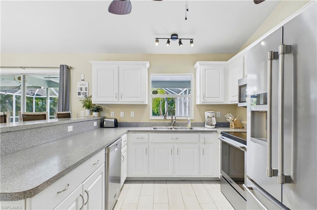 Kitchen featuring white cabinetry, light-toned countertops, and stainless steel appliances
