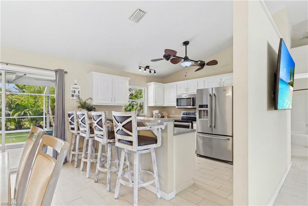 Kitchen featuring white cabinetry, stainless steel appliances, a breakfast bar with seating, and tile flooring