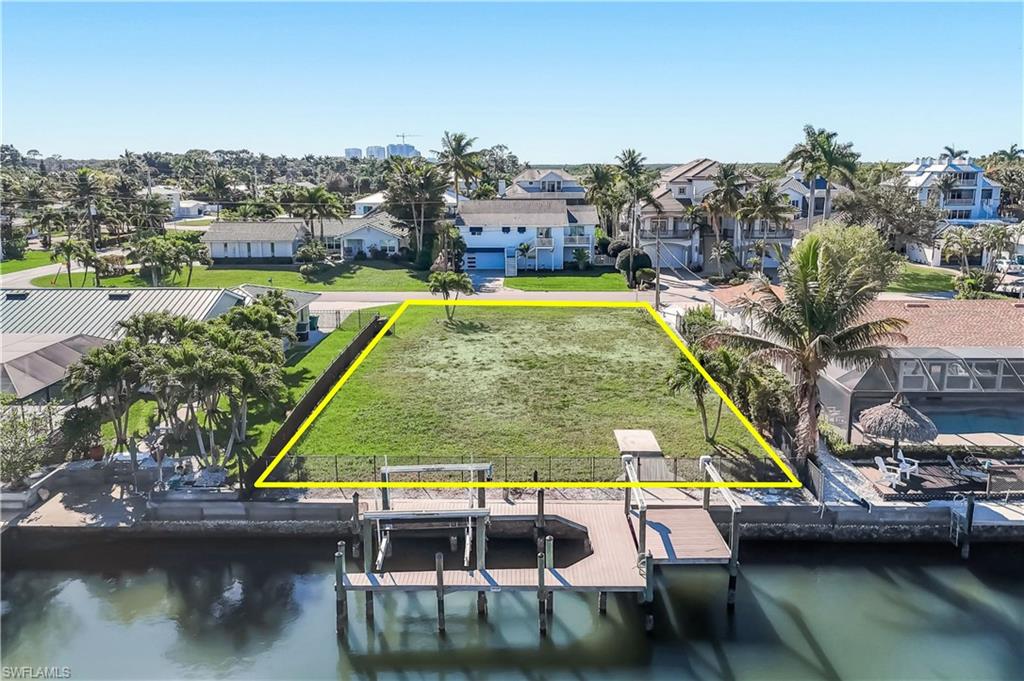 Waterfront parcel featuring a manicured lawn, an existing dock, and a boat lift - Virtually Edited Image