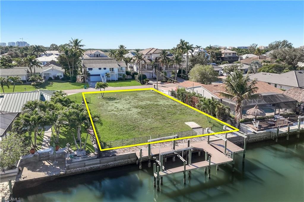 Waterfront parcel featuring a boat dock with a lift, direct canal access, and a clear, level building site - Virtually Edited Image