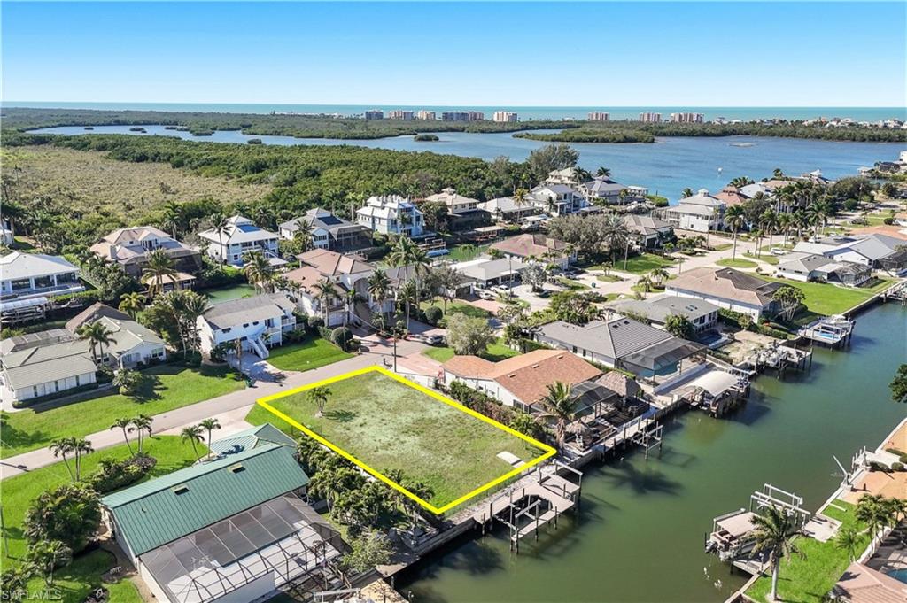 Expansive waterfront lot featuring direct canal access, mature palm trees, and clear sky - Virtually Edited Image