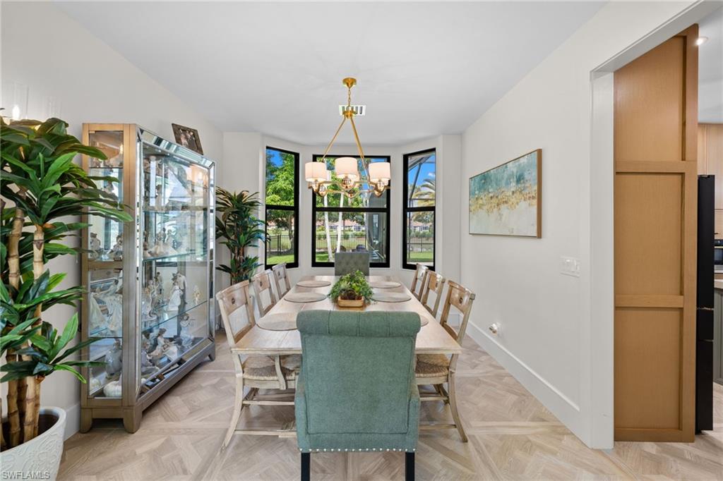 Dining area featuring a bay window, wood-finish flooring, white walls, and a contemporary chandelier