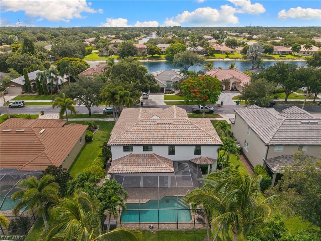 Two-story residence featuring a barrel tile roof, screened-in pool enclosure, and an attached covered patio