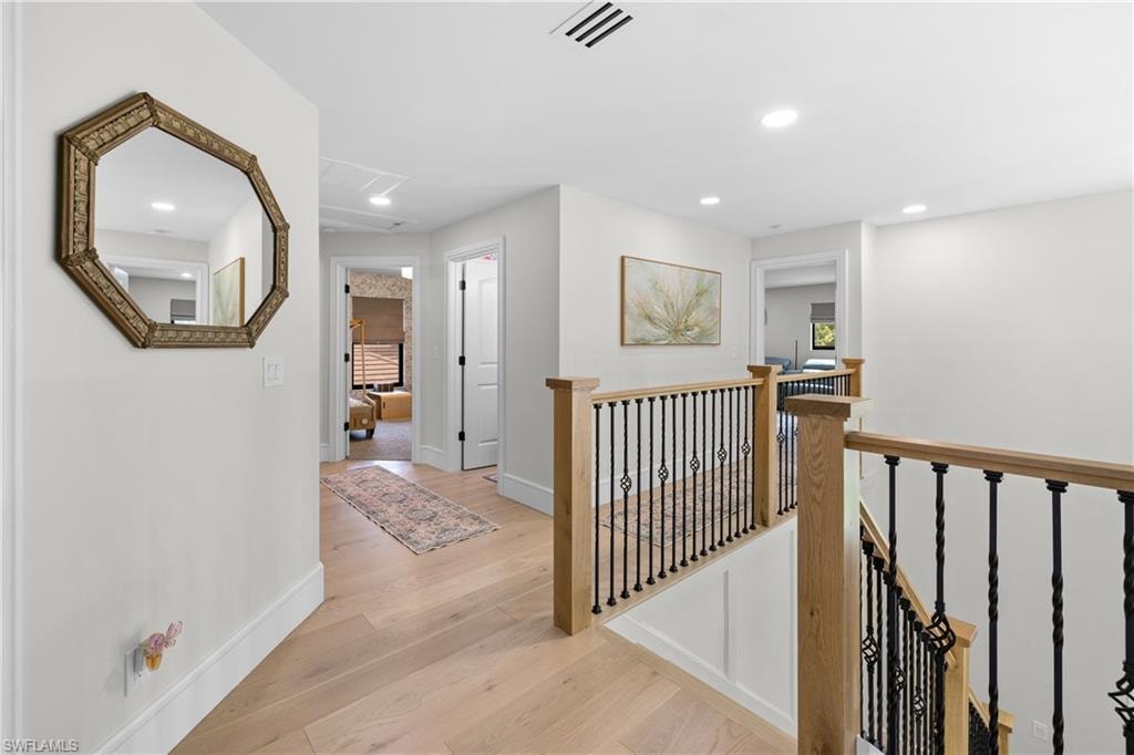 Upper-level hallway featuring light wood-finish flooring, recessed lighting, and white trim