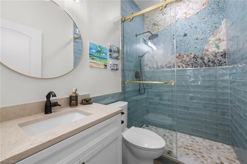 Bathroom featuring a glass-enclosed shower with custom mosaic tile and blue subway tile surround