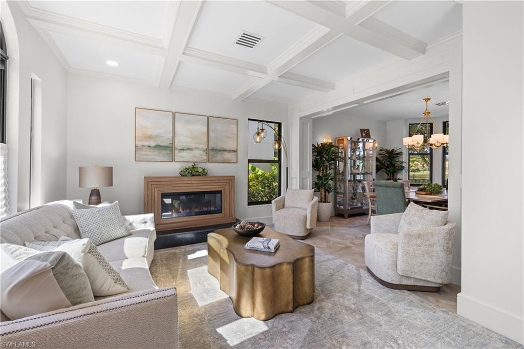 Living area featuring a coffered ceiling, a contemporary fireplace with a wood surround, and light-tone flooring