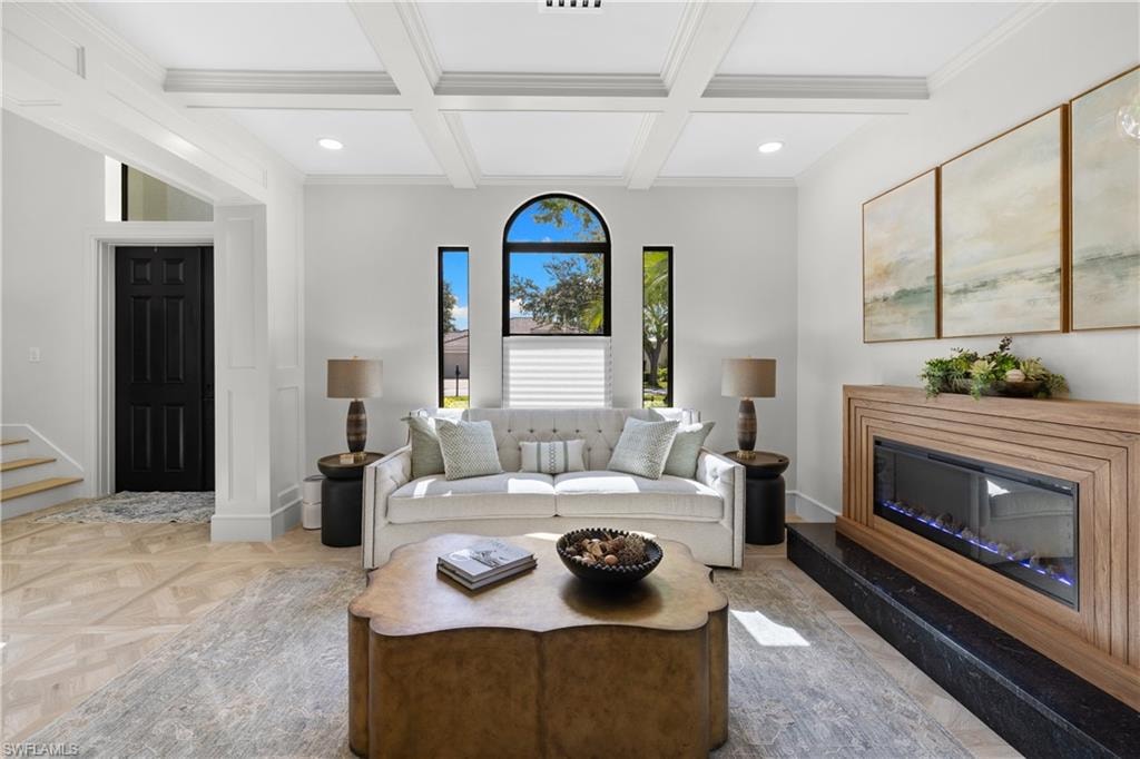 Spacious living area featuring coffered ceilings, an arched window, and a built-in electric fireplace with a wood-finish surround