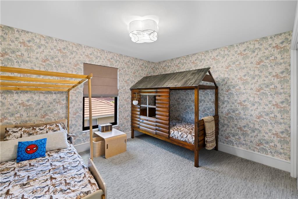 Room featuring patterned wallpaper, light-toned carpet flooring, and a flush-mount ceiling light fixture