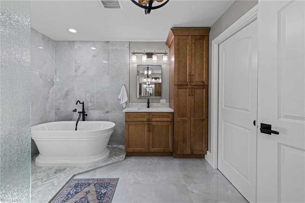 Freestanding soaking tub with matte black fixtures set against large format porcelain tile