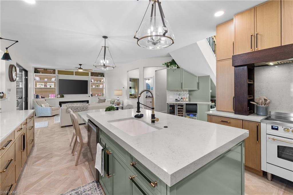 Open-concept kitchen featuring a large central island with an undermount sink, light-toned countertops, and a white range