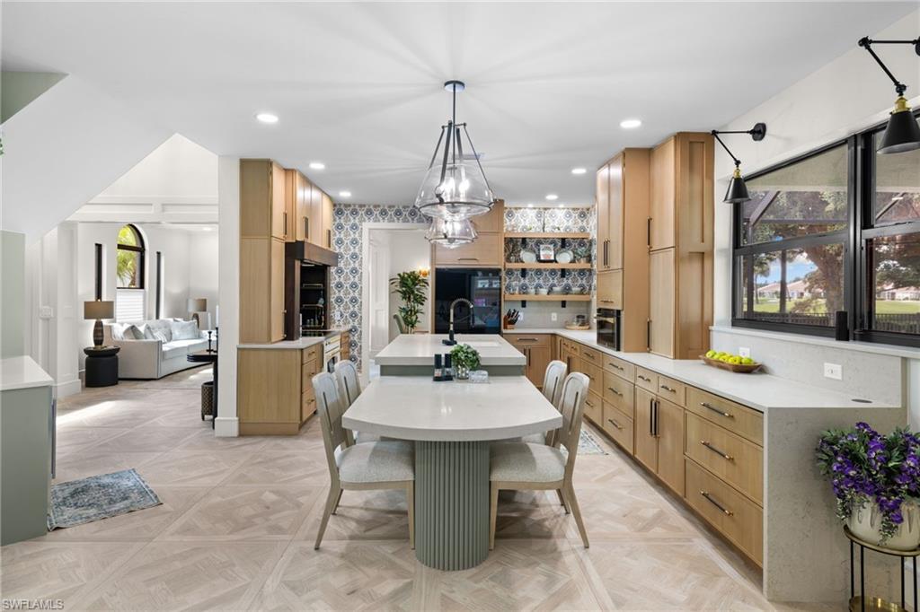 Open concept kitchen featuring wood-finish cabinetry, light-toned countertops, geometric tile flooring, and island seating
