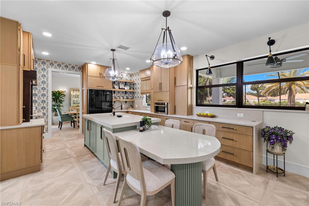 Spacious kitchen featuring light wood cabinetry, a large center island with integrated seating, and dual pendant lighting