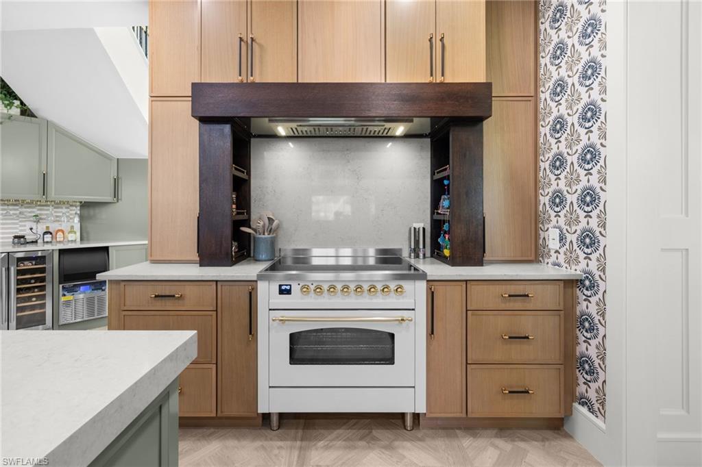 Gourmet kitchen featuring a white range, custom wood cabinetry, light countertops, wood-finish flooring, and a patterned accent wall
