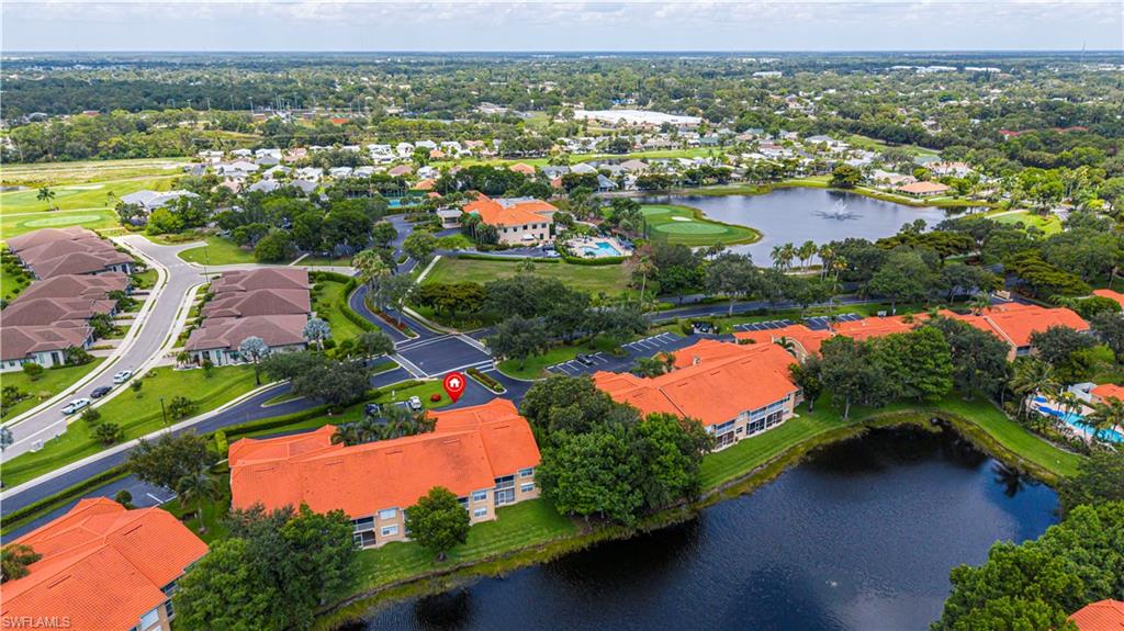 Aerial perspective showcasing residential buildings with terracotta-style roofs, surrounded by mature trees and manicured green spaces