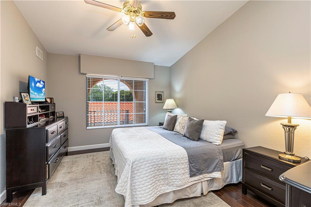 Vaulted ceiling with a ceiling fan, wood-finish flooring, a window with horizontal blinds, and a neutral wall color