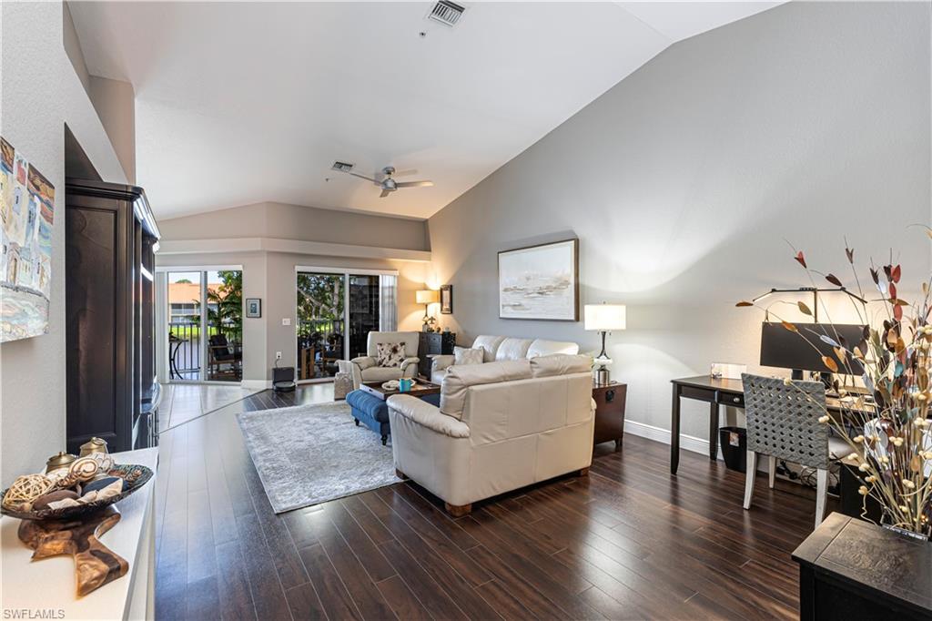 Spacious living area featuring wood-finish flooring, vaulted ceilings, and a ceiling fan