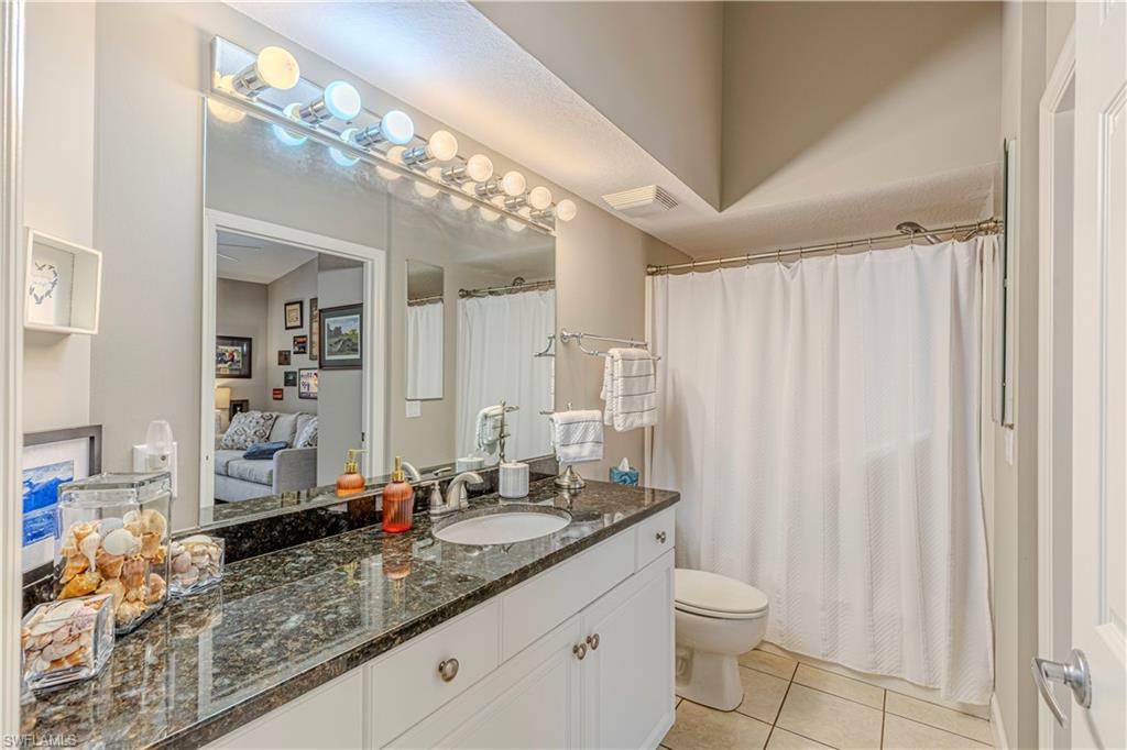 Bathroom featuring a vanity with a dark speckled countertop, an undermount sink, and polished chrome fixtures