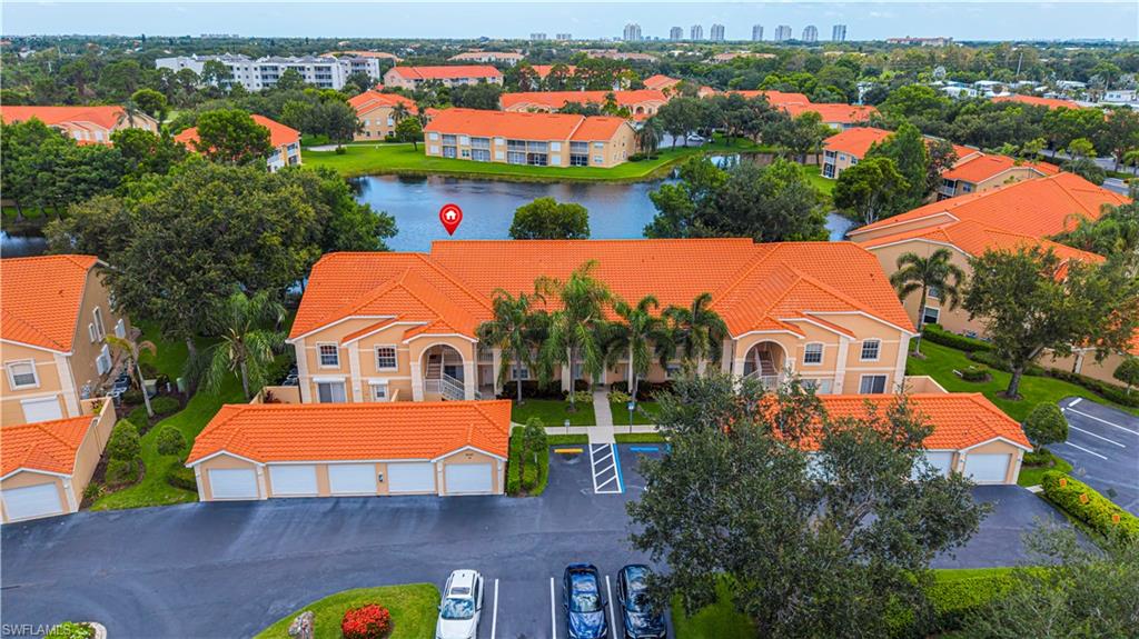 Low-rise condominium building featuring a vibrant orange tile roof, stucco exterior, and private balconies