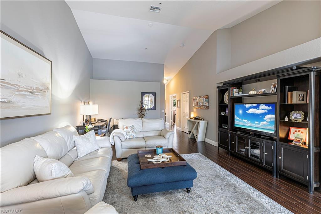 Living area featuring vaulted ceilings, wood-finish flooring, and light gray wall tones