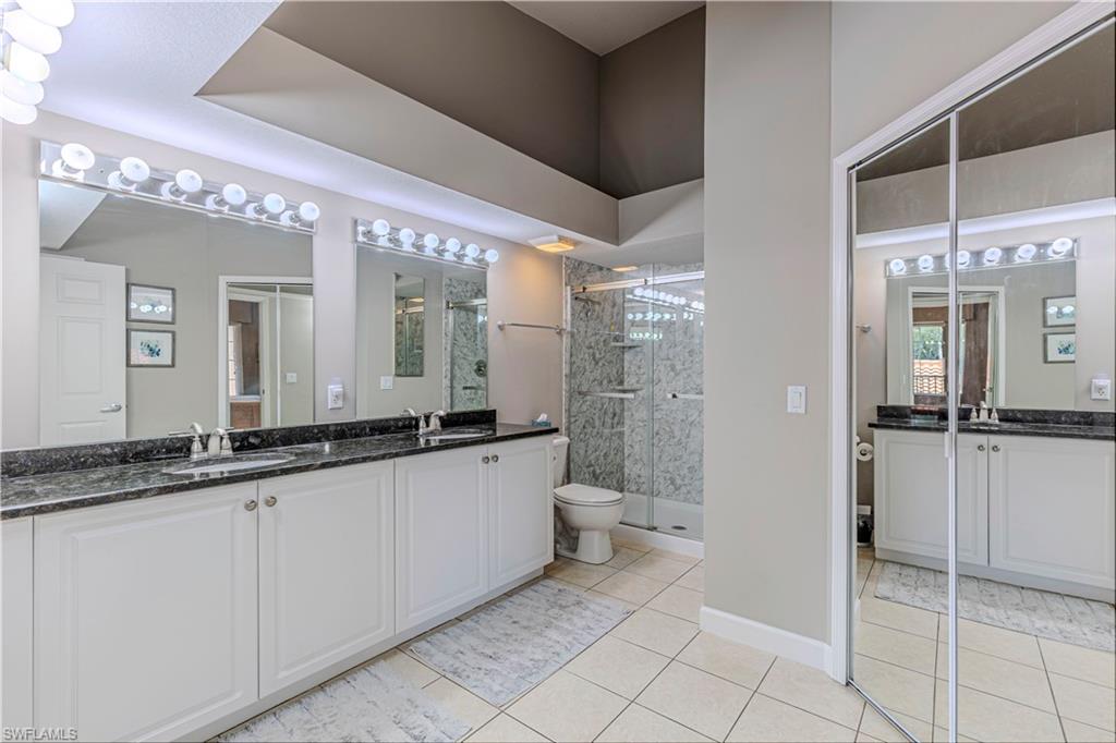 Bathroom featuring a double vanity with two undermount sinks, a dark countertop, and white cabinetry