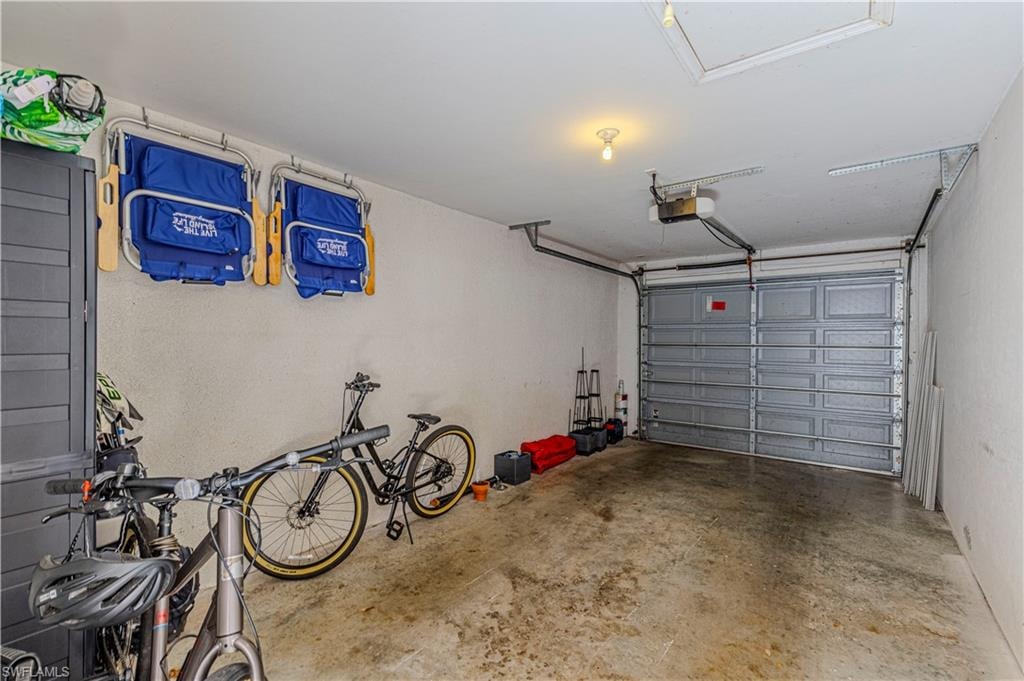 Attached garage featuring a sectional overhead door with opener, painted concrete flooring, and ceiling-mounted light fixture