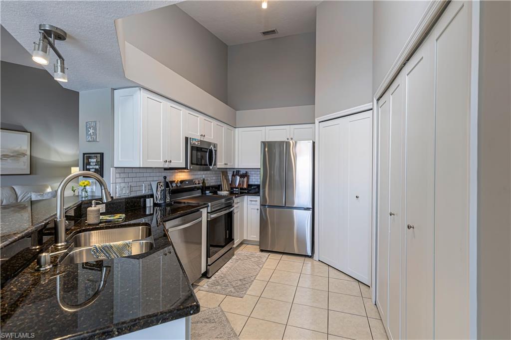 Contemporary kitchen featuring white cabinetry, dark stone countertops, and stainless-steel appliances