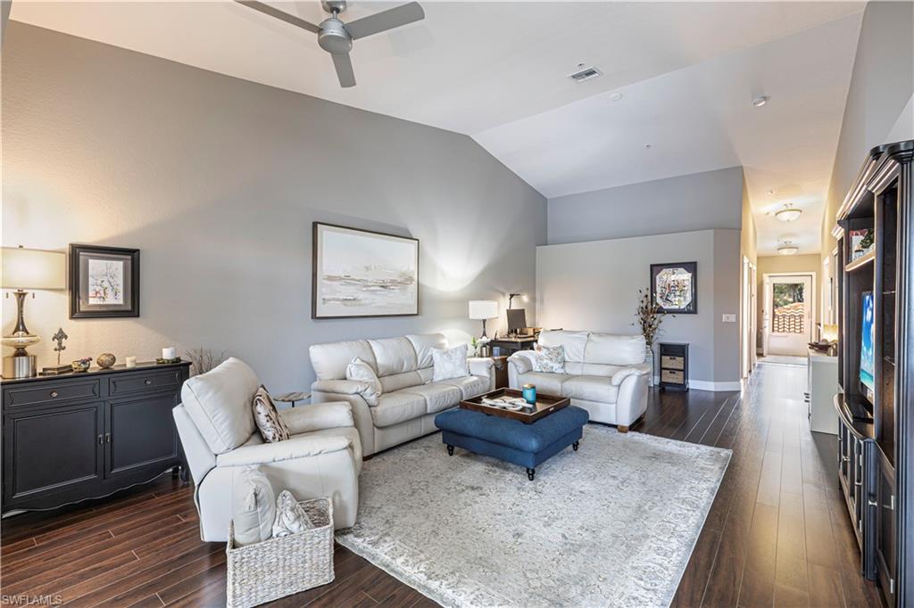 Spacious living area featuring vaulted ceilings, wood-finish flooring, and recessed lighting