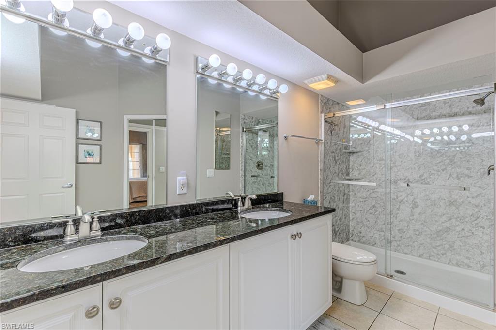 Dual vanity with granite countertops, white cabinetry, and undermount sinks