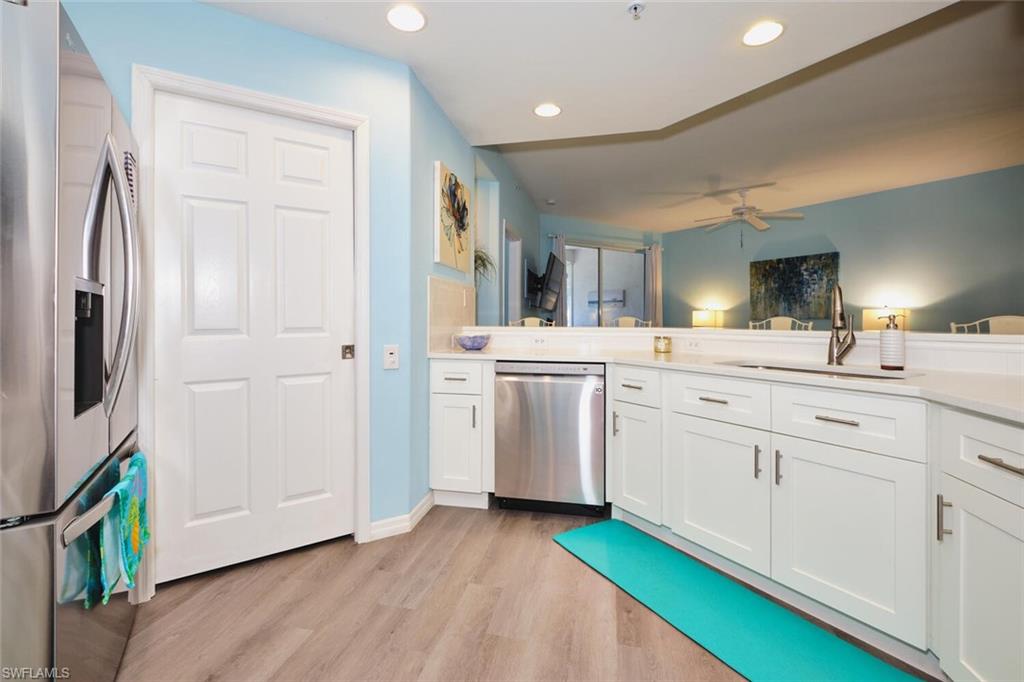 Kitchen with stainless steel appliances, a ceiling fan, light wood finished floors, white cabinetry, and recessed lighting