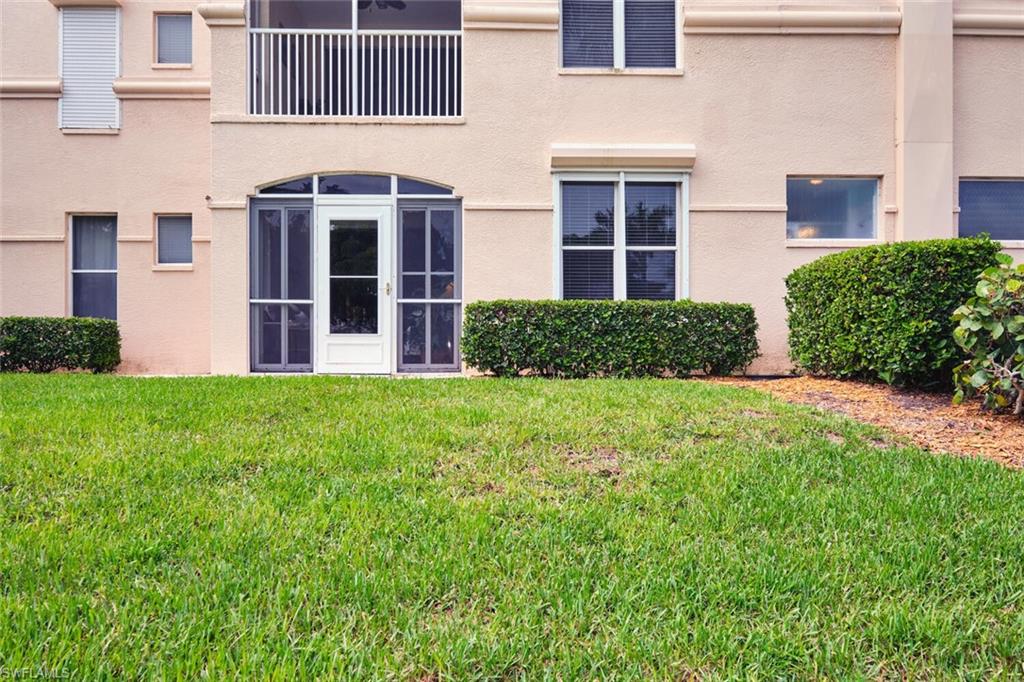 Rear view of property featuring a lawn and stucco siding