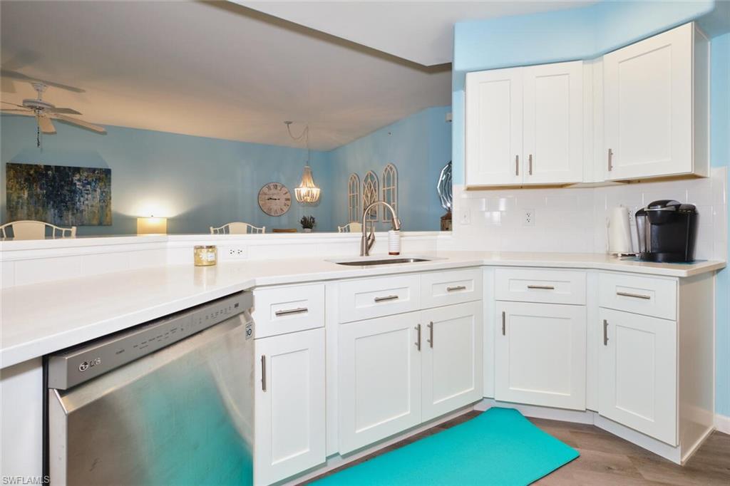Kitchen featuring stainless steel dishwasher, a ceiling fan, white cabinetry, decorative backsplash, and wood finished floors