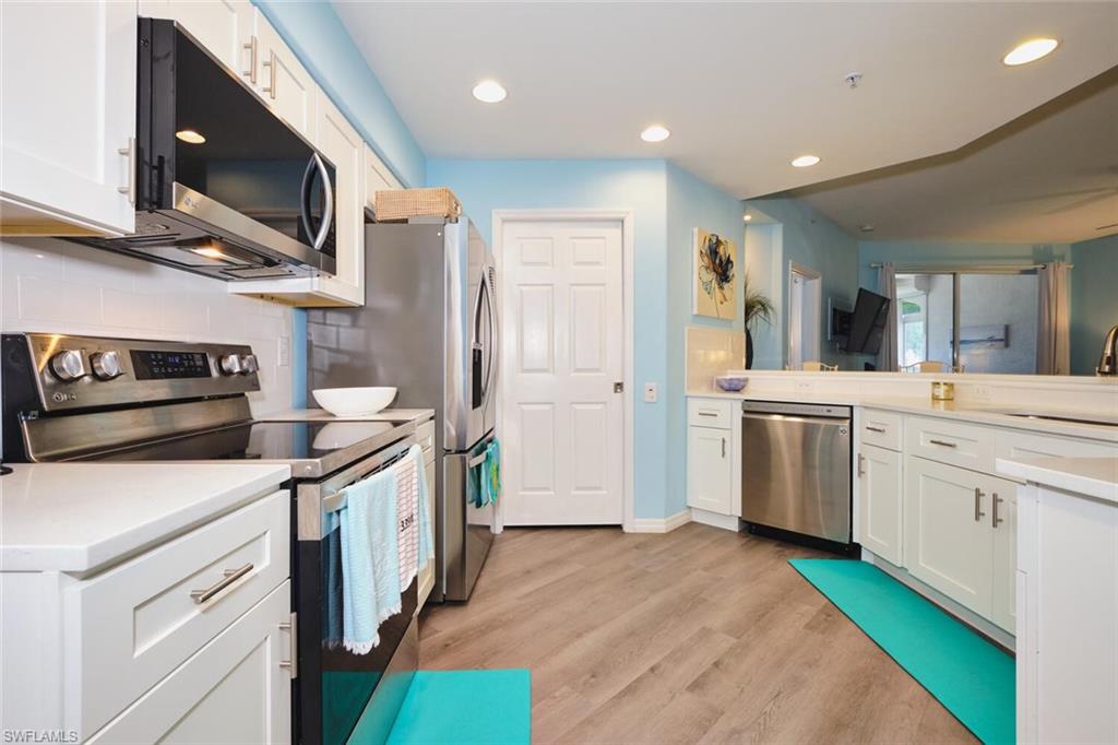 Kitchen featuring appliances with stainless steel finishes, white cabinetry, tasteful backsplash, light wood-style floors, and recessed lighting
