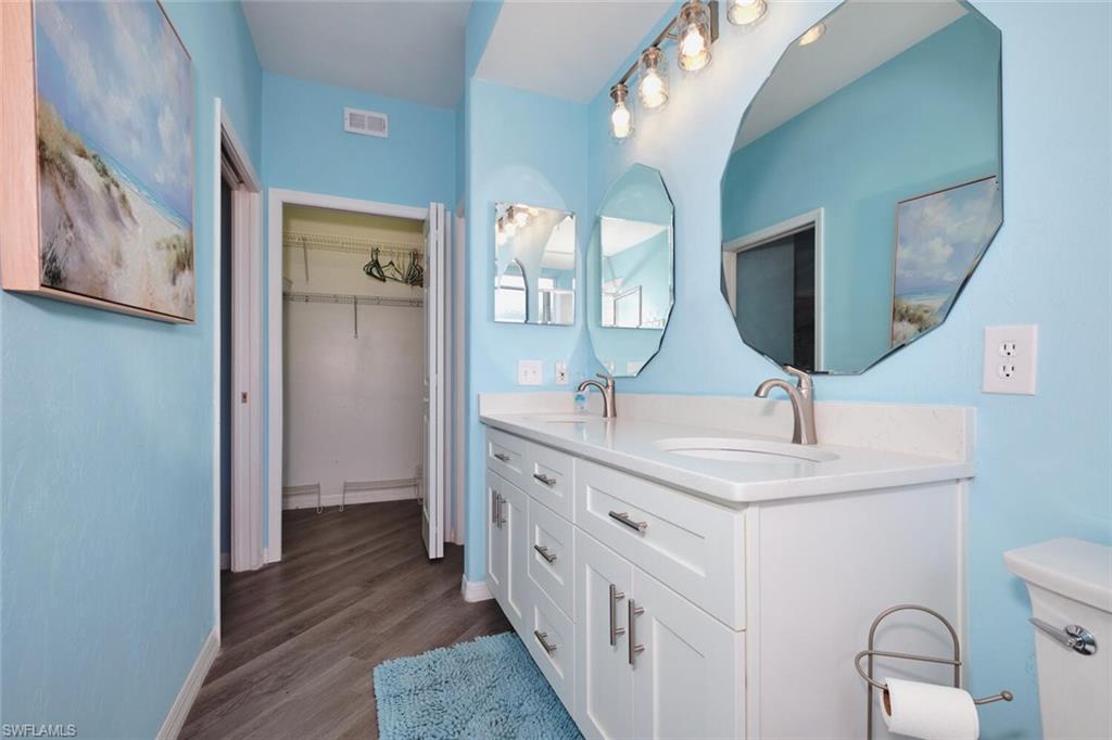 Bathroom with double vanity, wood finished floors, and a spacious closet