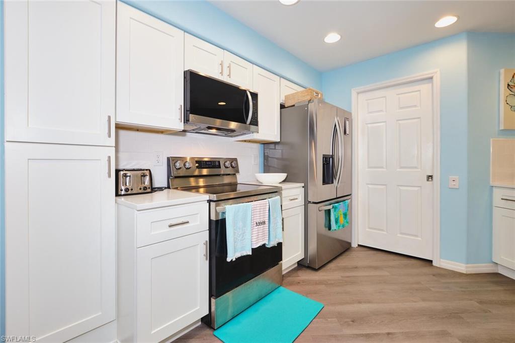 Kitchen featuring appliances with stainless steel finishes, light countertops, white cabinetry, light wood-style floors, and recessed lighting