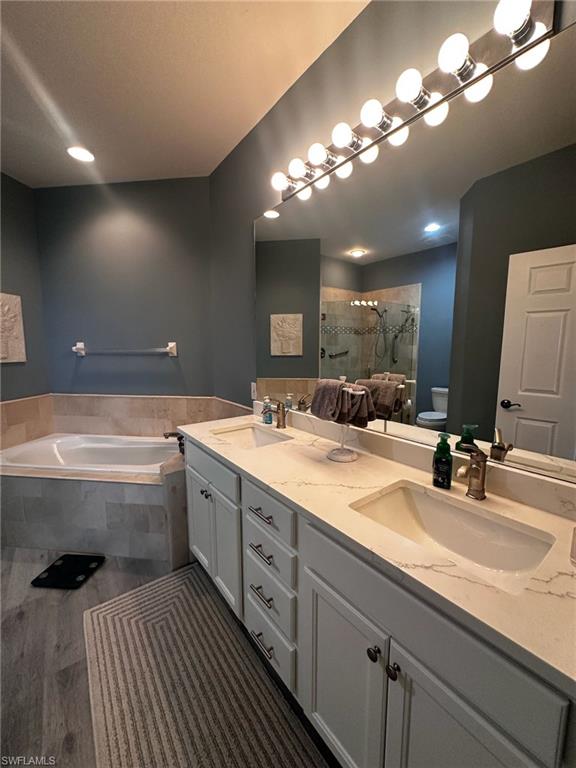 Full bath featuring a bath, double vanity, and a stall shower