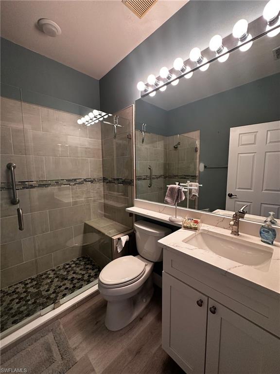 Bathroom with wood finished floors, a stall shower, and vanity