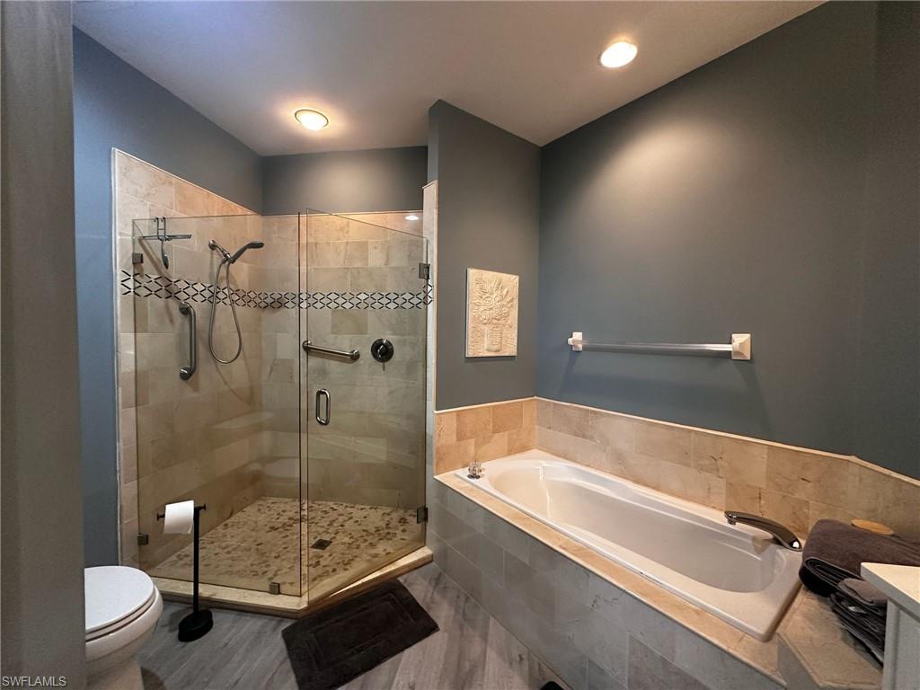 Full bathroom featuring a garden tub, a stall shower, wood finished floors, and vanity