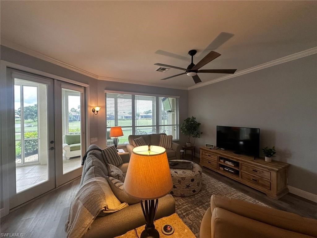 Living area with french doors, wood finished floors, ornamental molding, and ceiling fan