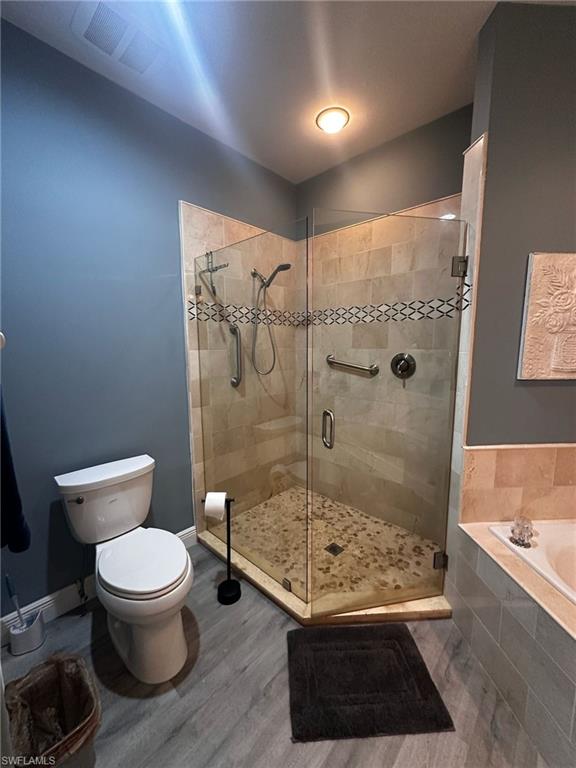 Full bathroom with wood finished floors, a garden tub, and a shower stall