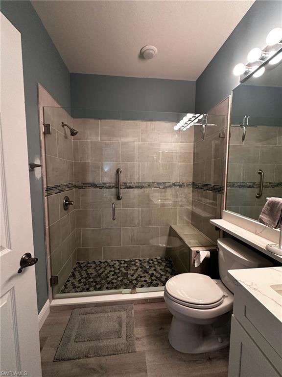 Full bath with vanity, a stall shower, and wood finished floors